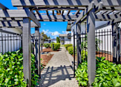 Thumbnail 9 of 33 - A pathway is framed by a pergola and leads to a building.