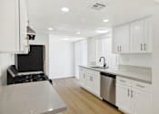 Thumbnail 16 of 31 - Modern kitchen with white cabinets and stainless appliances at Coventry Square Apartments, California, 97186