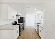 Thumbnail 31 of 31 - Galley kitchen with white cabinetry and recessed lighting at Coventry Square Apartments, Upland, CA