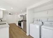 Thumbnail 21 of 31 - Kitchen with laundry room and modern appliances at Coventry Square Apartments, Upland, 97186