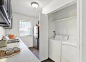 Thumbnail 19 of 21 - A small kitchen with a refrigerator, washer and dryer.