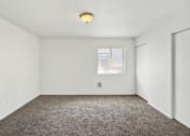 Thumbnail 20 of 21 - A room with a carpeted floor and a window with blinds.