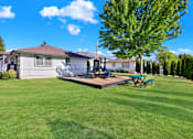 Thumbnail 11 of 21 - A house with a green lawn and a tree in front.