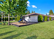 Thumbnail 14 of 21 - A house with a green lawn and a slide in the backyard.