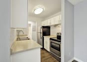 Thumbnail 25 of 28 - A kitchen with white cabinets and a black refrigerator.