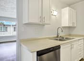 Thumbnail 23 of 28 - A kitchen with white cabinets and a beige countertop.