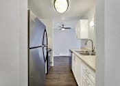 Thumbnail 26 of 28 - A kitchen with a stainless steel refrigerator and white cabinets.