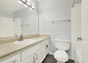 Thumbnail 27 of 28 - A white toilet is in a bathroom with a sink and mirror.