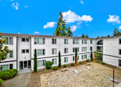 Thumbnail 3 of 28 - Apartment complex with a courtyard and trees.