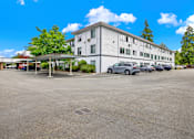 Thumbnail 16 of 28 - A large white building with a parking lot in front of it.