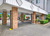 Thumbnail 7 of 28 - A parking lot with a building entrance supported by pillars.