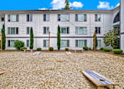 Thumbnail 17 of 28 - A building with a grey facade and a gravel yard with a bench.