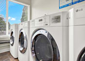 Thumbnail 9 of 28 - A row of LG front load washing machines are lined up in a store.