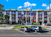 Thumbnail 14 of 25 - Two cars are parked in a parking lot in front of a red and white building. at Chateau La Fayette, California