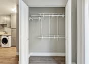 Thumbnail 8 of 25 - A white laundry room with a dryer and a white closet with shelves.at Federal Apartments, Los Angeles, CA 90025