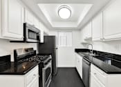 Thumbnail 25 of 41 - A black and white kitchen with white cabinets. at Elmwood Gardens, Burbank, California