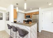Thumbnail 45 of 52 - A kitchen with a marble countertop and bar stools.