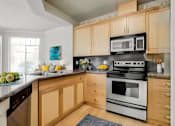 Thumbnail 42 of 52 - A kitchen with wooden cabinets and a black stove top oven.