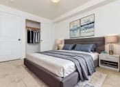 Thumbnail 25 of 52 - A bedroom with a bed, nightstand, and a painting on the wall.