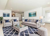 Thumbnail 46 of 52 - A living room with a white couch, a glass coffee table, and a blue rug.