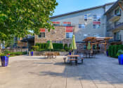 Thumbnail 3 of 52 - a patio with tables and umbrellas in front of an apartment building at Delano, Washington, 98052