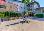 Thumbnail 15 of 52 - a patio with tables and umbrellas outside of an apartment building at Delano, Redmond, WA 98052