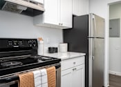 Thumbnail 30 of 60 - Kitchen with black appliances and white cabinets and a refrigerator at The Ridge at Bellevue, Bellevue, WA, Washington , 98005