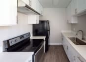 Thumbnail 3 of 5 - Kitchen With White Cabinetry And Black Appliances at Occidental Apartments, Los Angeles, CA