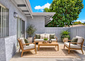 Thumbnail 5 of 31 - Outdoor patio with wooden furniture and privacy fence at Coventry Square Apartments, Upland