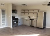Thumbnail 8 of 12 - Kitchen Area with Shelf Units, White Countertops, Stainless Steel Appliances, Hardwood Flooring at Wilson Apartments in Glendale, CA