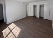 Thumbnail 7 of 11 - A room with wooden flooring and white walls with a window casting a shadow on the floor.