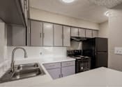 Thumbnail 1 of 22 - A kitchen with a stainless steel sink and white countertop.