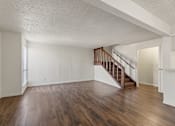 Thumbnail 16 of 22 - A room with wooden floors and a staircase.