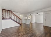 Thumbnail 13 of 22 - A room with wooden floors and a staircase with wooden railings.