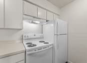 Thumbnail 17 of 22 - A white kitchen with a stove and refrigerator.