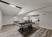 Thumbnail 21 of 28 - A pool table in a room with wooden flooring.