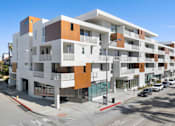 Thumbnail 2 of 12 - A modern multi-story building with a white and brown facade.