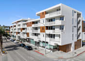 Thumbnail 1 of 12 - A modern apartment building with white and brown exterior.