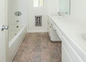 Thumbnail 21 of 27 - A white bathroom with a tiled floor and a window.