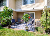 Thumbnail 2 of 16 - A patio with a table and chairs surrounded by plants.