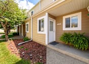 Thumbnail 1 of 16 - A beige house with a white door and windows.