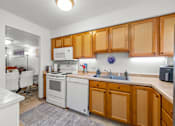 Thumbnail 8 of 16 - A kitchen with wooden cabinets and white appliances.