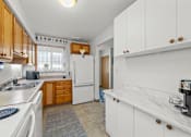 Thumbnail 9 of 16 - A kitchen with white cabinets and a white fridge.
