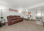 Thumbnail 11 of 16 - A living room with a brown leather couch and a glass coffee table.