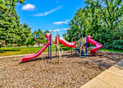 Thumbnail 5 of 16 - A playground with a red slide and a blue sky.