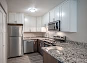 Thumbnail 3 of 8 - A kitchen with a granite countertop and stainless steel appliances.