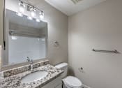 Thumbnail 6 of 8 - A bathroom with a sink, toilet, mirror, and lights.