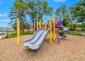 Thumbnail 7 of 27 - A playground with a purple slide and yellow poles.