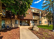 Thumbnail 1 of 15 - A large rock sits in the middle of a grassy area in front of a building.