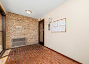 Thumbnail 3 of 15 - A hallway with a brick wall and a bulletin board on the wall.